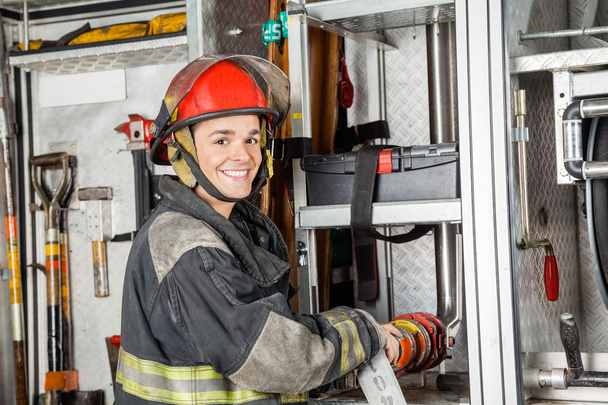 Happy Firefighter Fixing Water Hose In Truck - Photo, image