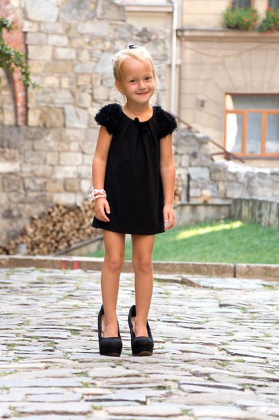 маленька дівчинка, одягнена як доросла жінка. в туфлях на високих підборах
 - Фото, зображення