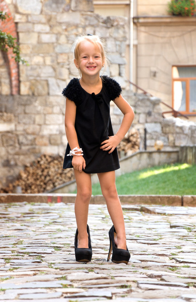 маленька дівчинка носить взуття і стоїть на дорозі в місті
 - Фото, зображення