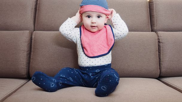 Caucasian baby boy weared bib  sitting on sofa at home - Foto, immagini