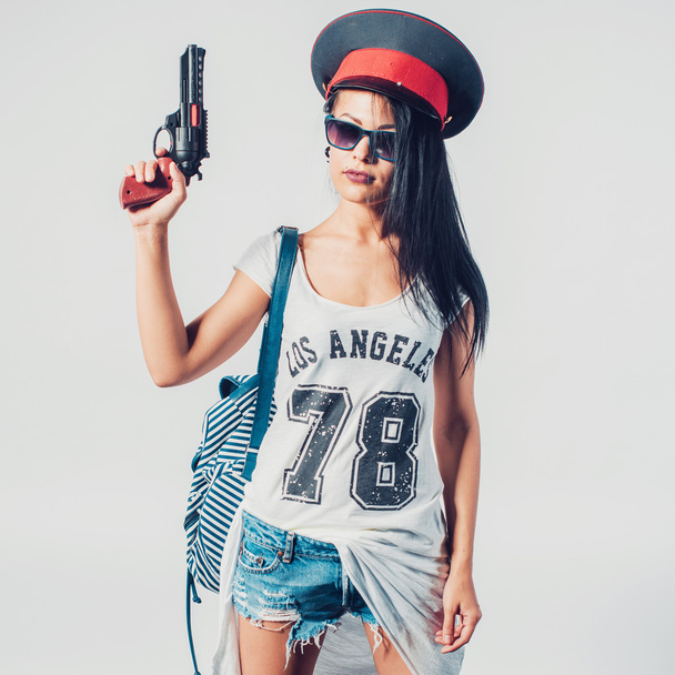 Moda swag sexy chica sosteniendo juguete pistola mujer divertirse usando la tapa de la policía
. - Foto, imagen