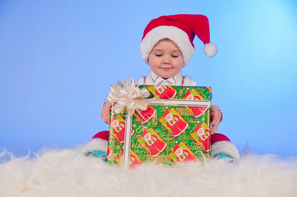 Funny laughing baby in Santa suit with a present box. - Фото, изображение