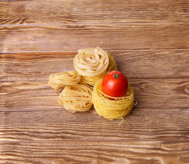 Pasta spaghetti noodles with r and tomatoes on wooden table - Φωτογραφία, εικόνα