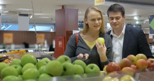 Szczęśliwa młoda para kupować jabłek w supermarkecie - Materiał filmowy, wideo