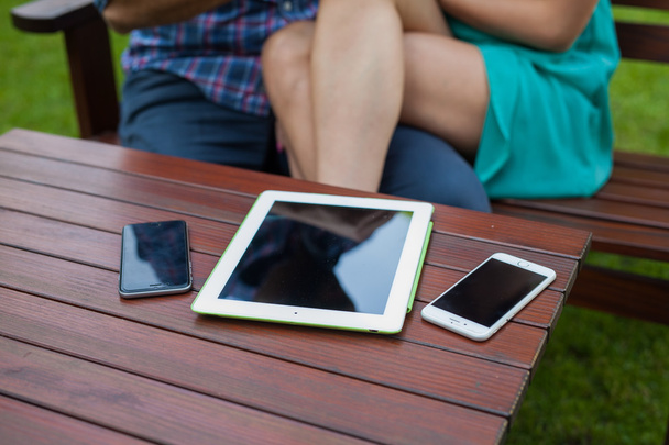 tablet, smartphones  near sitting couple. - Zdjęcie, obraz