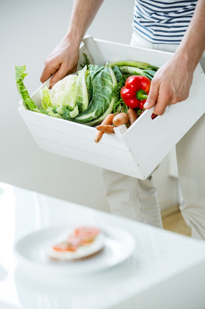 El hombre lleva la caja con verduras, compras de comestibles
 - Foto, imagen