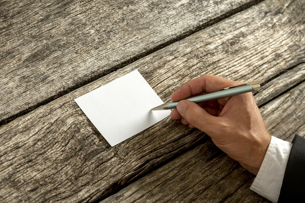 Overhead view of a hand in elegant suit writing on blank white c - Φωτογραφία, εικόνα
