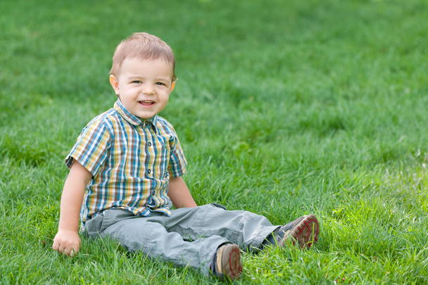 Sonriente niño contra la hierba verde de verano
 - Foto, Imagen