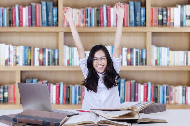 Étudiante levant la main dans la bibliothèque tout en étudiant
 - Photo, image