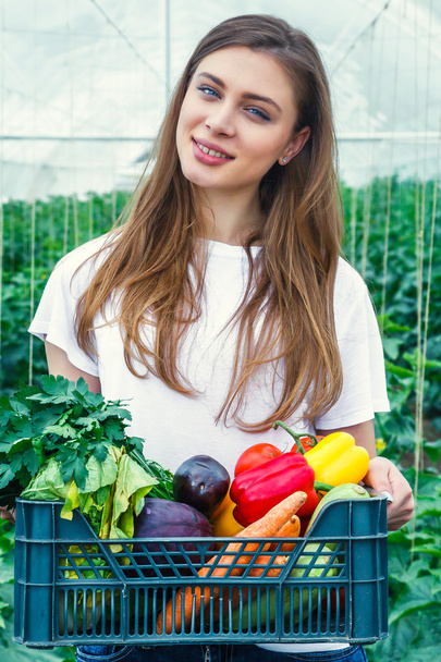 Girl holding a box with ecological vegetables. - 写真・画像