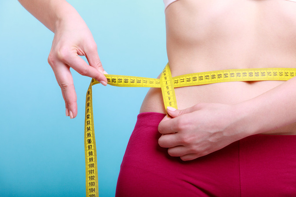 Diet. Fitness woman fit girl with measure tape measuring her waist - Fotó, kép