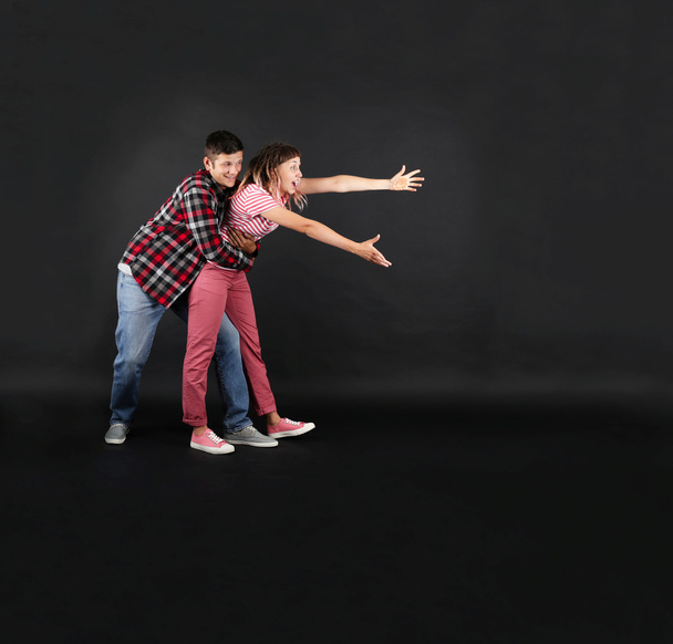 Emotional young couple on black background - Фото, изображение