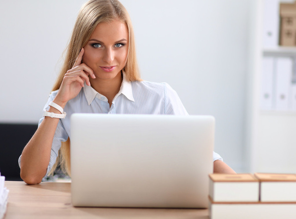 Jolie femme d'affaires assise sur un bureau avec ordinateur portable dans le bureau - Photo, image