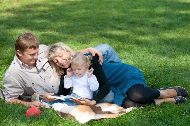 Mamá leyendo a su familia fuera
 - Foto, Imagen