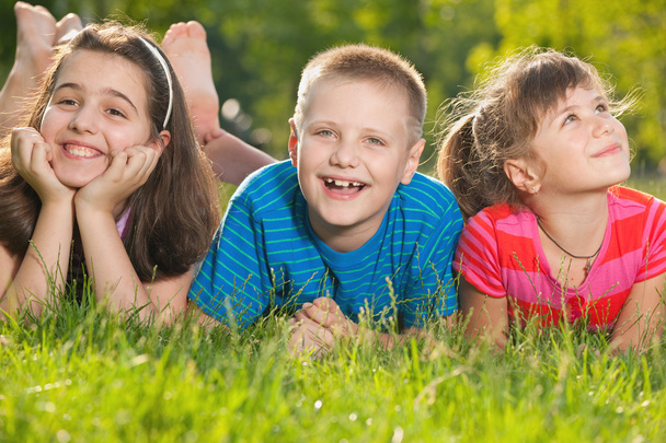 Trois enfants heureux sur l'herbe
 - Photo, image