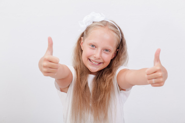Retrato de uma menina bonita mostrando polegares para cima no branco
 - Foto, Imagem
