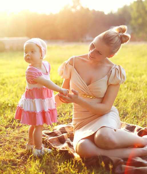 Feliz jovem mãe e bebê pequena filha vestindo um vestido toge
 - Foto, Imagem