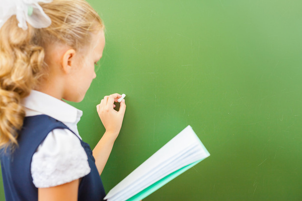 Écolière de première année a écrit sur le tableau noir avec de la craie en classe
 - Photo, image