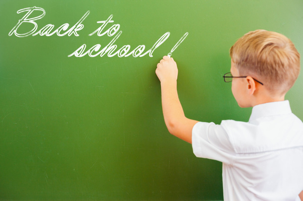 First grade schoolboy wrote on blackboard with chalk at classroom - Фото, зображення