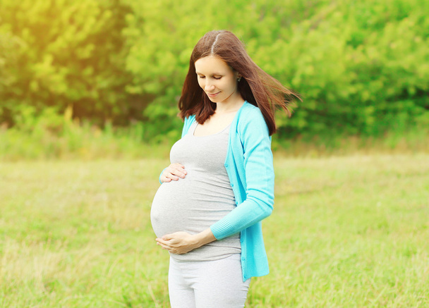 Portrait of pregnant young woman outdoors in warm summer day  - Photo, Image