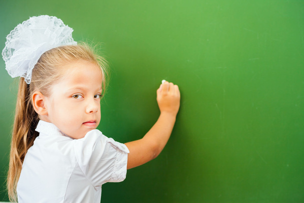 First grade schoolgirl wrote on blackboard with chalk at classroom - Φωτογραφία, εικόνα