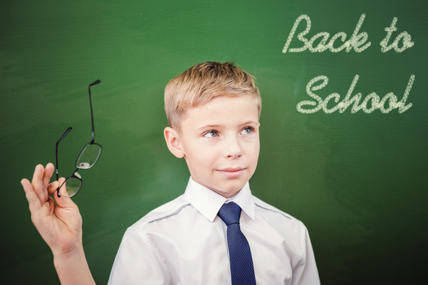 Schoolboy looking to blackboard with text of back to school - Foto, afbeelding