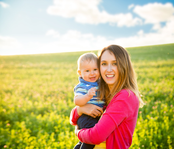 Fiatal, boldog anya gyermekével mosolygó szabadtéri - Fotó, kép