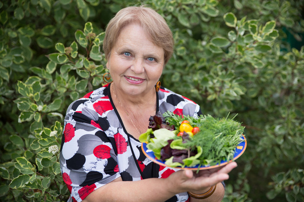 Happy pensioner woman with vegetables at dacha - Foto, Imagem