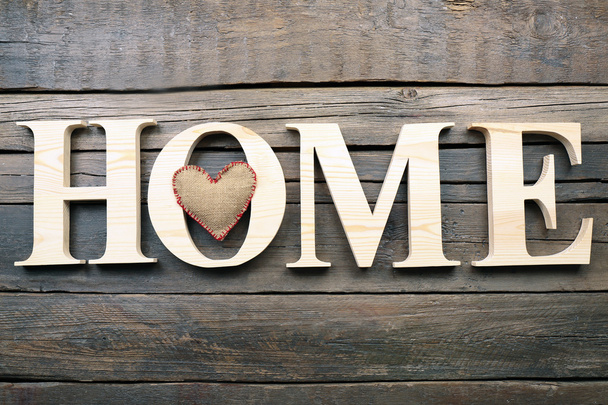 Decorative letters forming word HOME with heart on wooden background - Foto, immagini