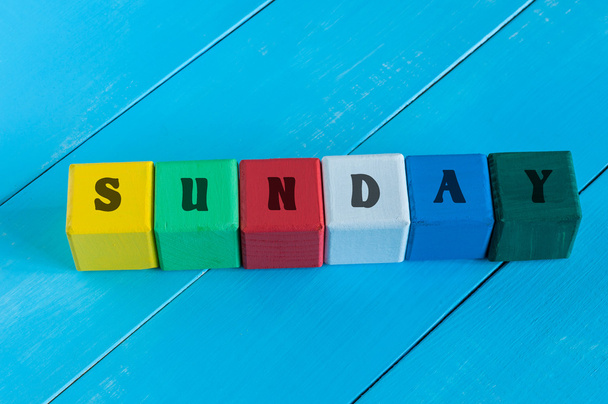 Слово Неділя, написане в дитячому кольорі дерев'яні кубики, на фоні світло-блакитного дерева
. - Фото, зображення