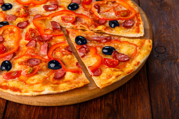 Delicious pizza with sausages, peppers and olives - Фото, зображення
