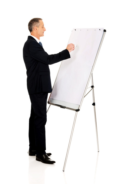 Male executive writing on a flipchart - Foto, afbeelding