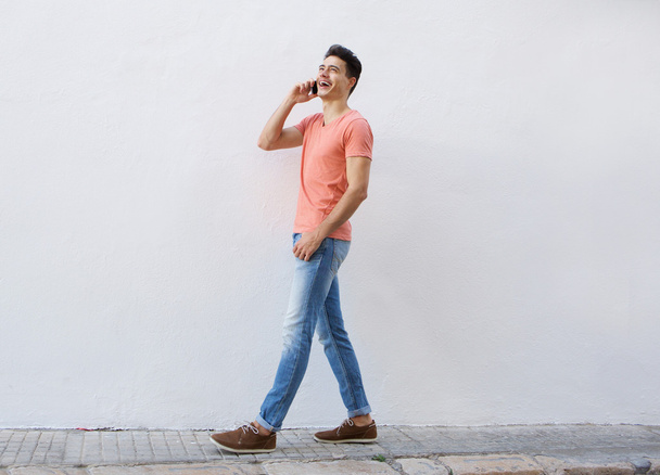 Hymyilevä mies kävelee ja kuuntelee matkapuhelinta
  - Valokuva, kuva