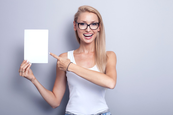Smiling young blonde woman with empty card. - Photo, Image