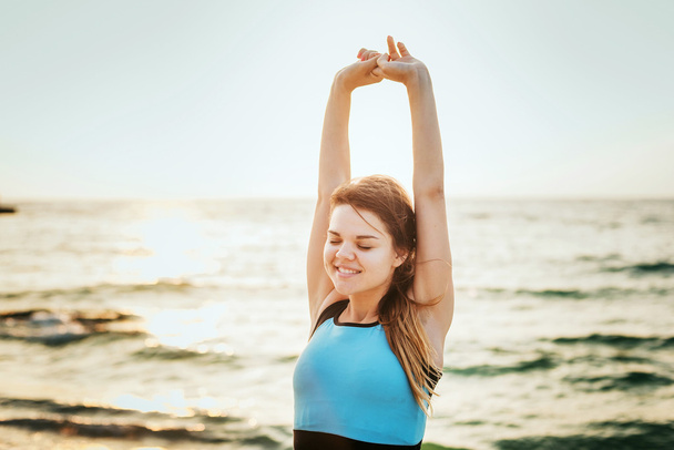 Fitness spor modeli mutlu gülümseyerek gündoğumu açık çalışma sırasında egzersizleri yapıyor. Güzel beyaz kadın eğitim dışında sahil sabah - Fotoğraf, Görsel