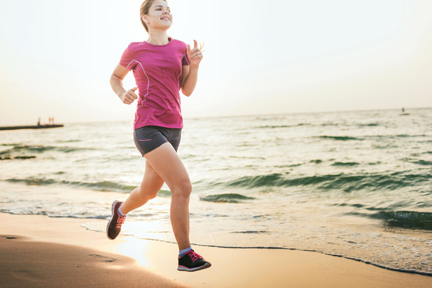Running vrouw. Vrouwelijke atleet joggen tijdens de Sunrise periode op strand. - Foto, afbeelding