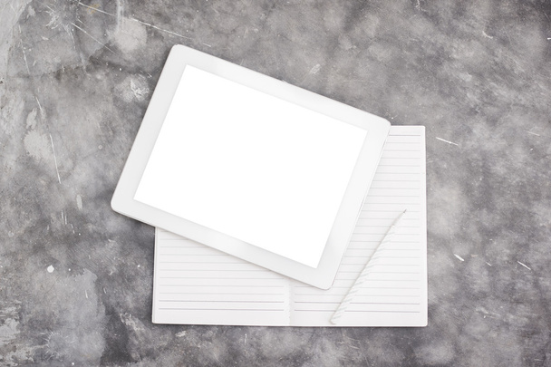 Blank digital tablet and notebook on a concrete background - Foto, imagen