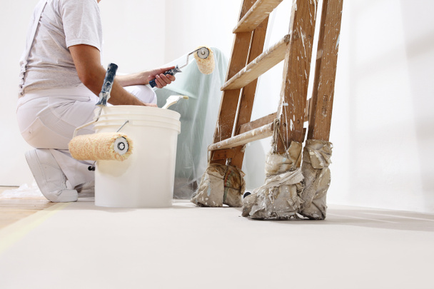 pintor hombre en el trabajo con un rodillo, cubo y escala, vista inferior
 - Foto, Imagen