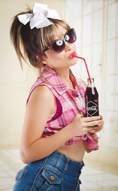 Beautiful retro girl holding an old vintage coca cola bottle - Фото, изображение