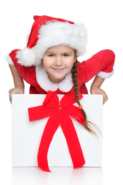 Happy little girl in Santa hat looks out of gift box - Photo, Image