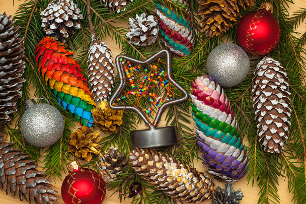 Christmas decorations background. Branches of pine needles with Christmas decorations, Christmas cones painted by hand paints, holiday star - Photo, Image