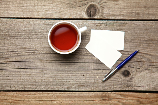 Biglietti da visita vuoti con penna e tazza di tè sul tavolo da ufficio in legno
 - Foto, immagini