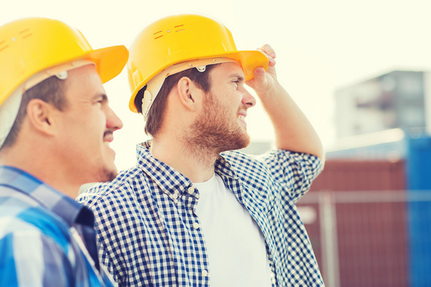 group of smiling builders in hardhats outdoors - Foto, Imagem