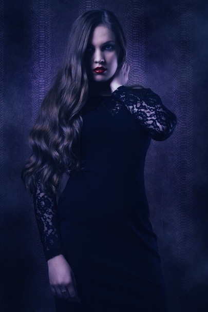 Pretty woman in a black dress in the dark room - Фото, изображение