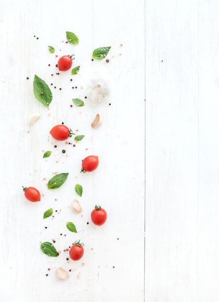 Cherry tomatoes, fresh basil leaves, garlic cloves and spices on rustic white wooden backdrop, top view - Photo, Image