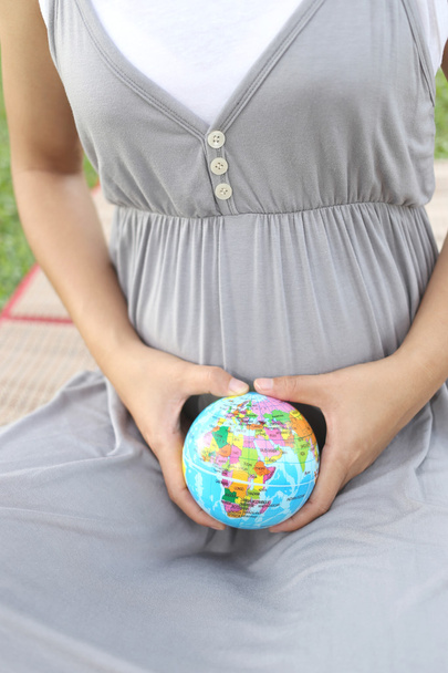 Zwangere vrouwen tonen Globe model in de hand. - Foto, afbeelding