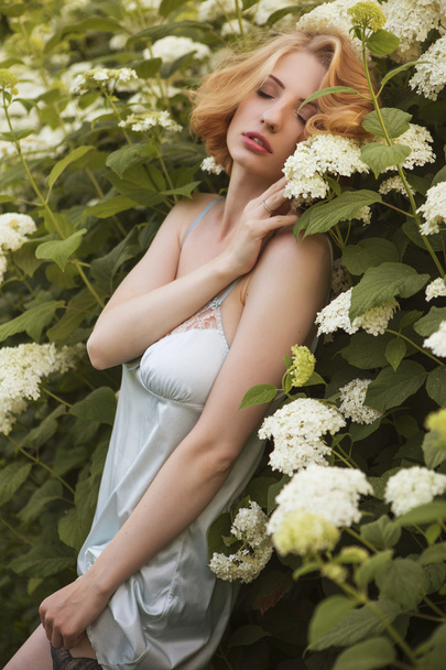 Όμορφη ξανθιά γυναίκα με σγουρά bob σύντομο hairstyle, λεπτή συνθέτουν και κόκκινα χείλη σε πράσινο κοντό φόρεμα στο πάρκο. Μόδα αισθησιακό ποζάρουν για καλοκαίρι ηλιοβασίλεμα. Σε εξωτερικούς χώρους - Φωτογραφία, εικόνα