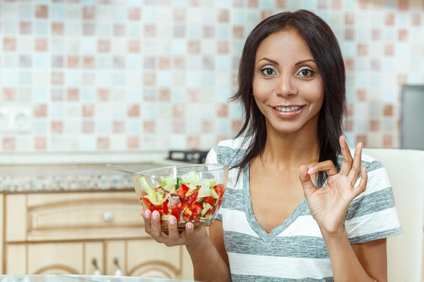 Beautiful woman eating fresh salad in modern kitchen - Foto, Imagem