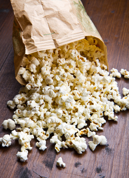A bowl of popcorn and kernelson a wooden table - Foto, imagen