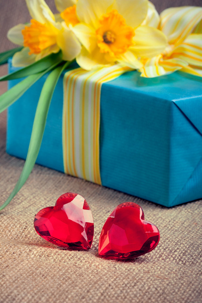 Dos corazones de cristal rojo con una caja de regalo y flores
 - Foto, imagen